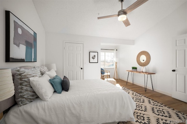 bedroom with ceiling fan, lofted ceiling, wood-type flooring, and a textured ceiling