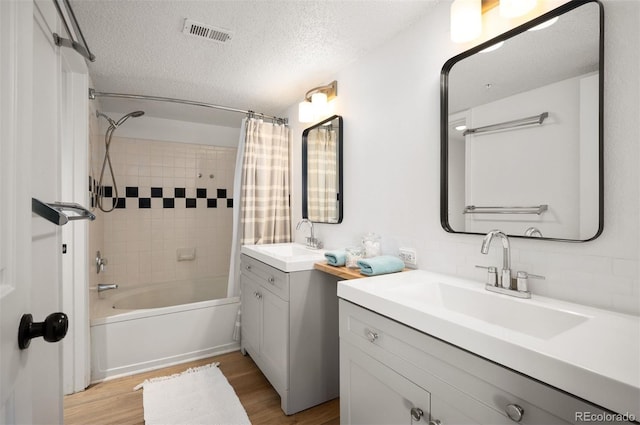 bathroom featuring wood-type flooring, vanity, a textured ceiling, and shower / bath combo