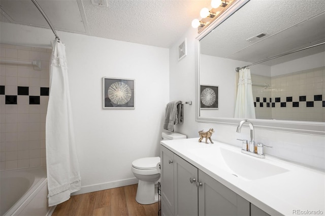 full bathroom featuring shower / tub combo with curtain, hardwood / wood-style flooring, vanity, a textured ceiling, and toilet