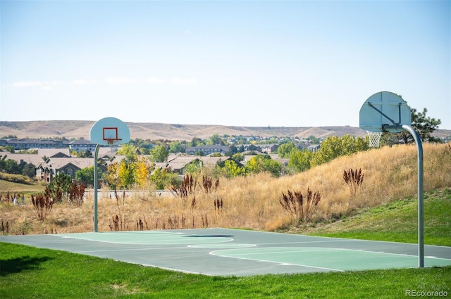 view of sport court featuring a mountain view and a lawn