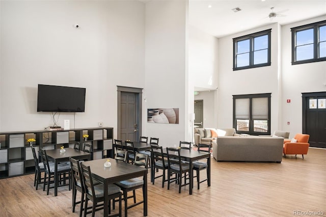 dining space featuring a towering ceiling and light hardwood / wood-style flooring