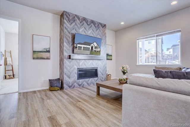 living room with a tile fireplace and hardwood / wood-style floors