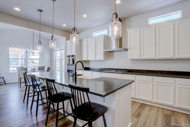 kitchen featuring white cabinets, a kitchen island with sink, a breakfast bar, and pendant lighting