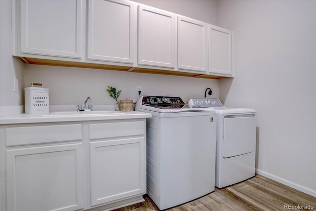 washroom with washer and dryer, light hardwood / wood-style flooring, cabinets, and sink