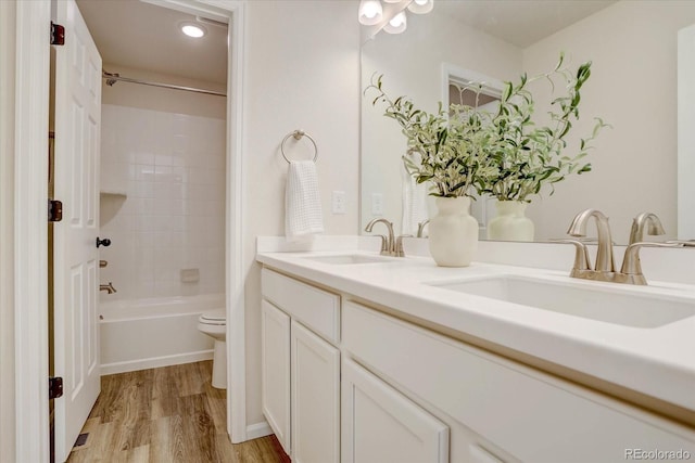 full bathroom with toilet, wood-type flooring, vanity, and tiled shower / bath combo