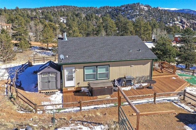 view of front of property featuring an outbuilding, a deck with mountain view, a view of trees, and a shed