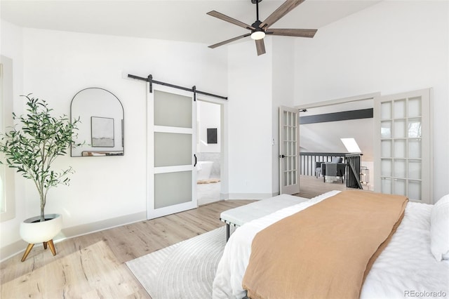 5814 Cole Way, Arvada, CO 80004 - bedroom with wood finished floors, a barn door, high vaulted ceiling, and connected bathroom