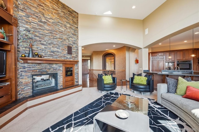 16134 Sandstone Dr, Morrison, CO 80465 - living area featuring carpet flooring, a towering ceiling, a stone fireplace, arched walkways, and recessed lighting