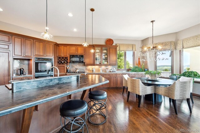 16134 Sandstone Dr, Morrison, CO 80465 - kitchen with black appliances, brown cabinetry, dark wood-style floors, backsplash, and recessed lighting