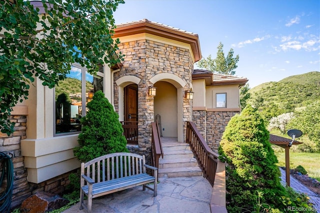 16134 Sandstone Dr, Morrison, CO 80465 - view of exterior entry featuring stone siding, stucco siding, and a tiled roof