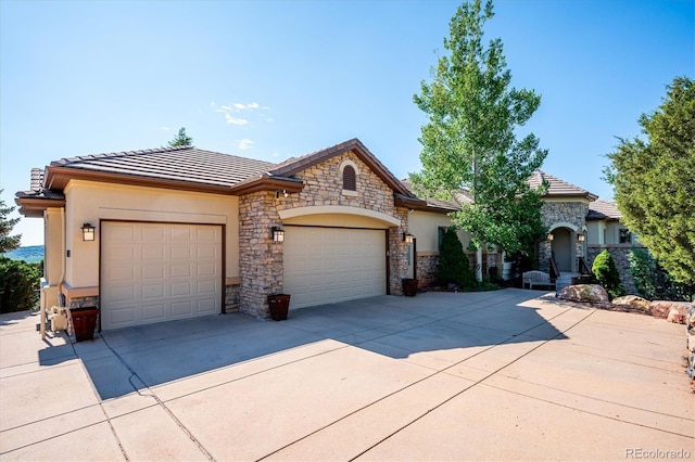 16134 Sandstone Dr, Morrison, CO 80465 - view of front of house featuring stone siding, a garage, driveway, and a tiled roof