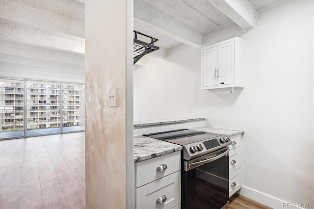 kitchen featuring white cabinets, a textured ceiling, light stone countertops, stainless steel electric range oven, and light hardwood / wood-style floors