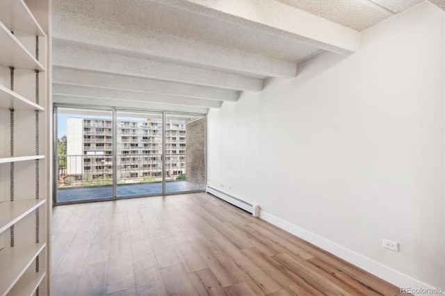 spare room featuring beam ceiling, a baseboard heating unit, hardwood / wood-style flooring, and a textured ceiling