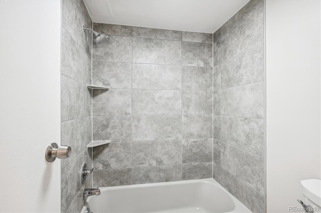 bathroom featuring tiled shower / bath combo and toilet