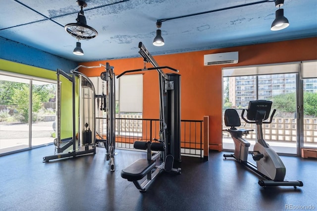 exercise room with a wall mounted air conditioner and a healthy amount of sunlight