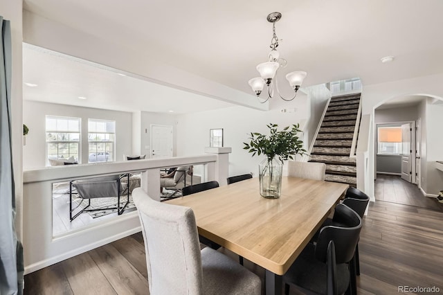 dining area with stairs, arched walkways, a chandelier, and dark wood finished floors