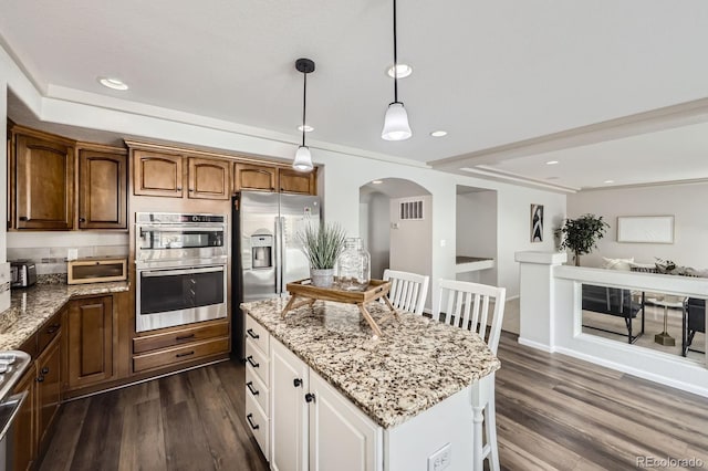 kitchen featuring arched walkways, light stone countertops, appliances with stainless steel finishes, and dark wood finished floors