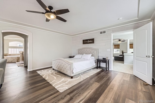 bedroom with arched walkways, baseboards, visible vents, and dark wood-type flooring