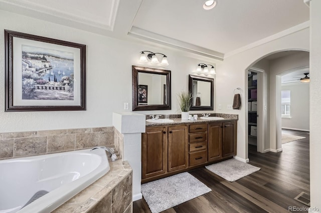 full bath with a sink, double vanity, a bath, and wood finished floors