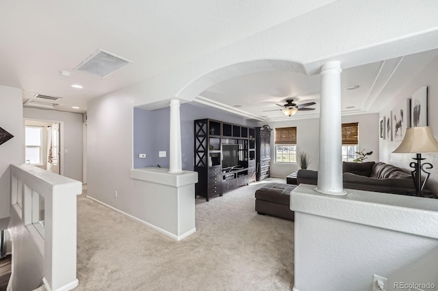 living area featuring visible vents, ornate columns, arched walkways, a ceiling fan, and carpet