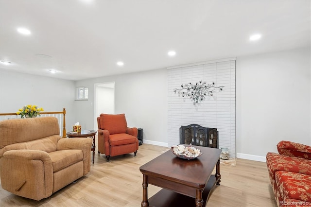 living room featuring a brick fireplace and light hardwood / wood-style flooring