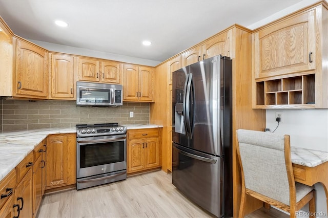 kitchen with light wood-type flooring, stainless steel appliances, and backsplash