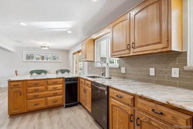 kitchen with dishwasher, sink, light stone countertops, light hardwood / wood-style floors, and kitchen peninsula