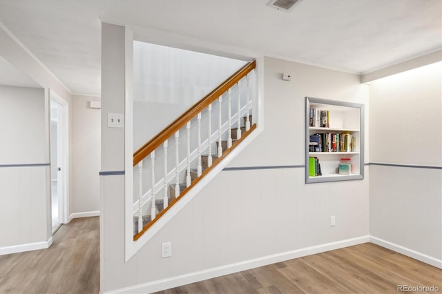 stairway featuring wood-type flooring and crown molding