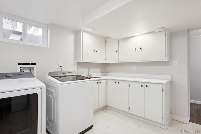 laundry room with cabinets, washing machine and dryer, and sink