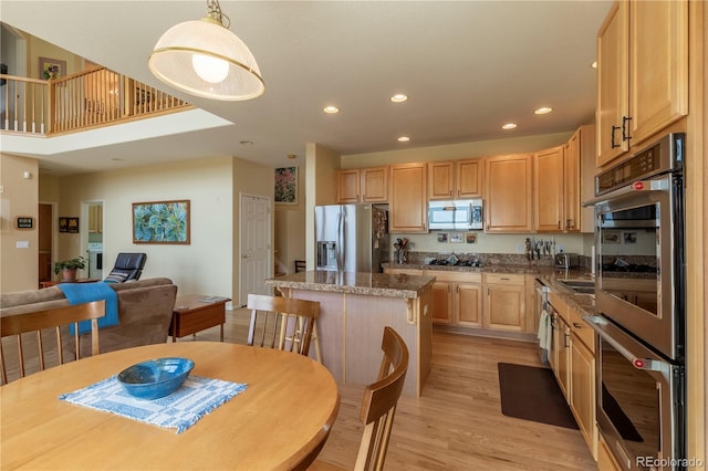 9586 W Victoria Dr, Littleton, CO 80128 - kitchen with a center island, light wood-style flooring, light brown cabinets, appliances with stainless steel finishes, and recessed lighting