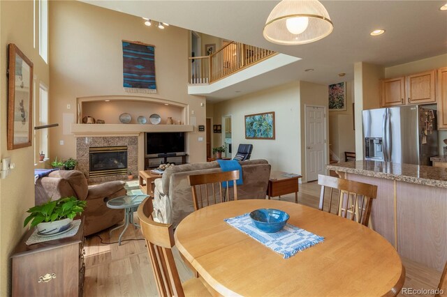 9586 W Victoria Dr, Littleton, CO 80128 - dining area with light wood-style flooring, a high ceiling, a high end fireplace, and recessed lighting