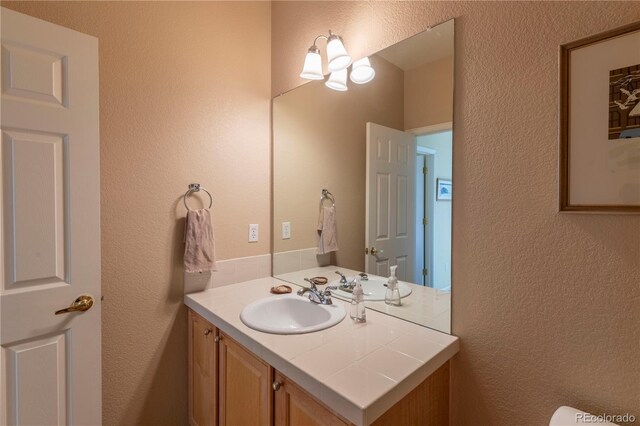 9586 W Victoria Dr, Littleton, CO 80128 - half bathroom featuring vanity and a textured wall