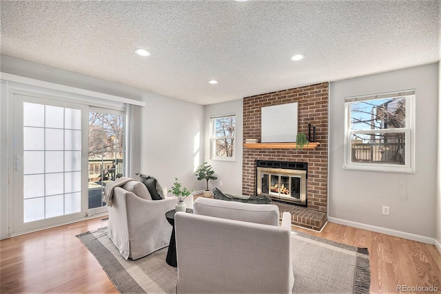 living room with plenty of natural light, light hardwood / wood-style floors, and a brick fireplace