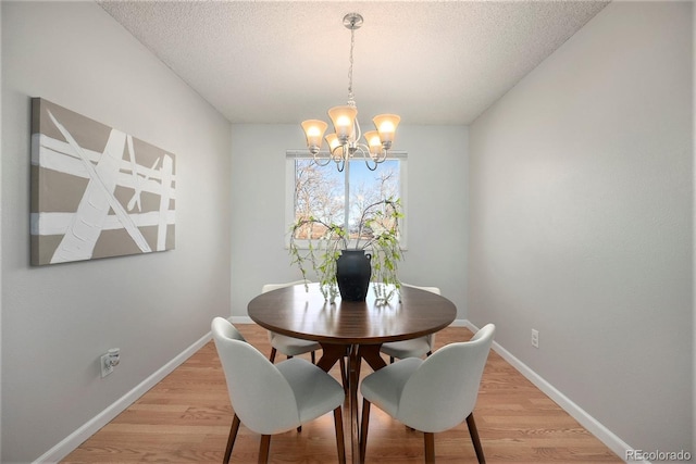 dining room with an inviting chandelier, light hardwood / wood-style flooring, and a textured ceiling