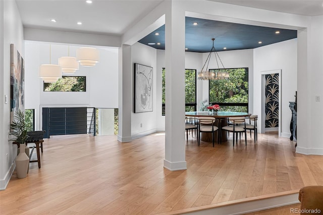 dining area featuring light hardwood / wood-style floors, a healthy amount of sunlight, and a notable chandelier