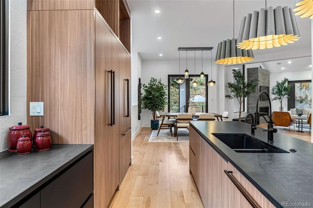 kitchen featuring sink, light wood-type flooring, and decorative light fixtures