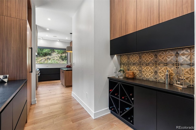 bar featuring pendant lighting, decorative backsplash, and light hardwood / wood-style flooring