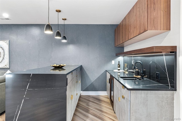 kitchen featuring hanging light fixtures, sink, and light hardwood / wood-style flooring