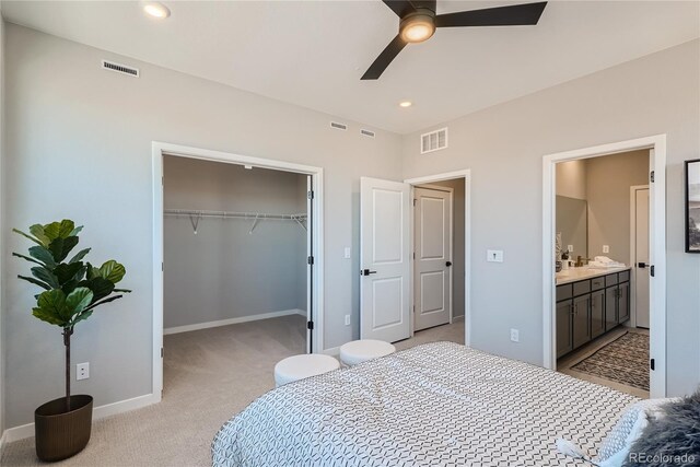 bedroom featuring ceiling fan, a closet, light colored carpet, and ensuite bath