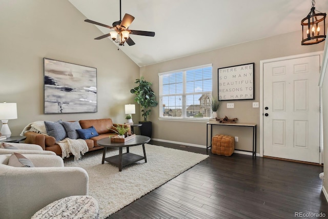 living area featuring high vaulted ceiling, ceiling fan with notable chandelier, dark wood-style floors, and baseboards