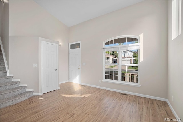 unfurnished room featuring a towering ceiling and light hardwood / wood-style floors