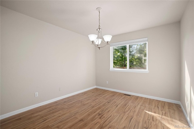 unfurnished room with a notable chandelier and wood-type flooring