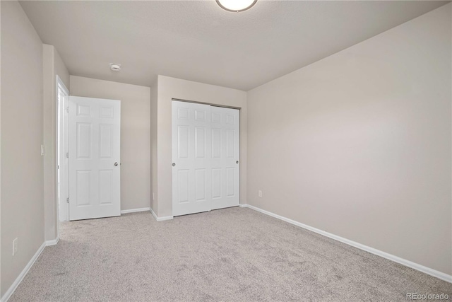 unfurnished bedroom featuring light carpet and a closet