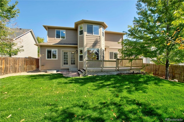 rear view of property featuring a wooden deck and a lawn