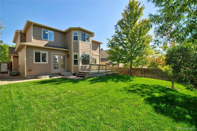 rear view of house featuring a wooden deck, a lawn, and french doors