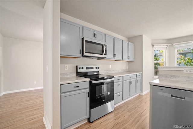 kitchen with gray cabinetry, light hardwood / wood-style floors, and appliances with stainless steel finishes