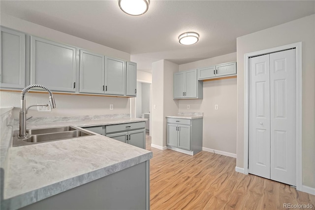 kitchen featuring sink, gray cabinets, a textured ceiling, and light wood-type flooring