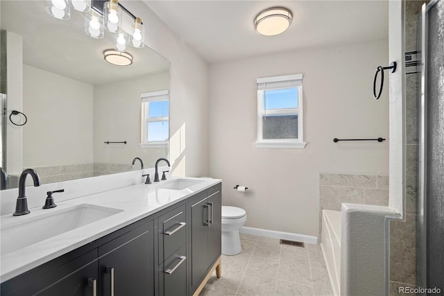 bathroom with a tub to relax in, tile patterned floors, vanity, and toilet