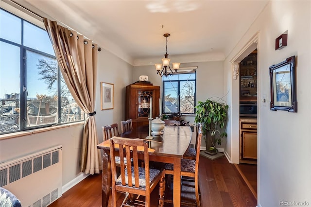 dining space featuring baseboards, dark wood-type flooring, an inviting chandelier, and radiator heating unit