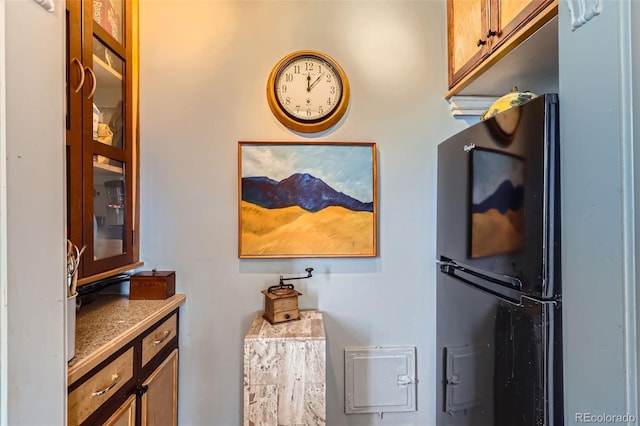 details with brown cabinetry, glass insert cabinets, and freestanding refrigerator